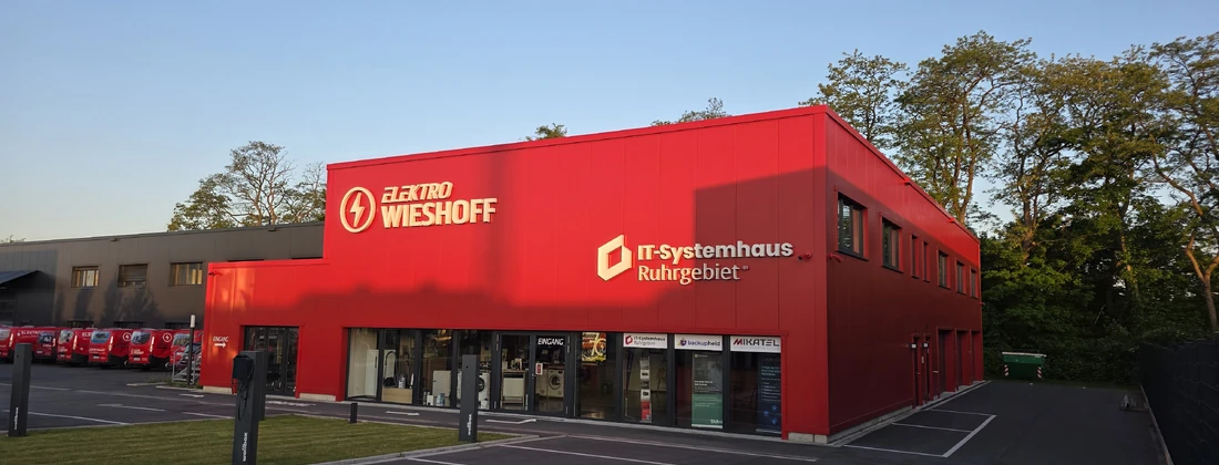 Rotes Gebäude mit dem Schriftzug 'IT-Systemhaus Ruhrgebiet' und 'Elektro Wieshoff' an der Fassade.
