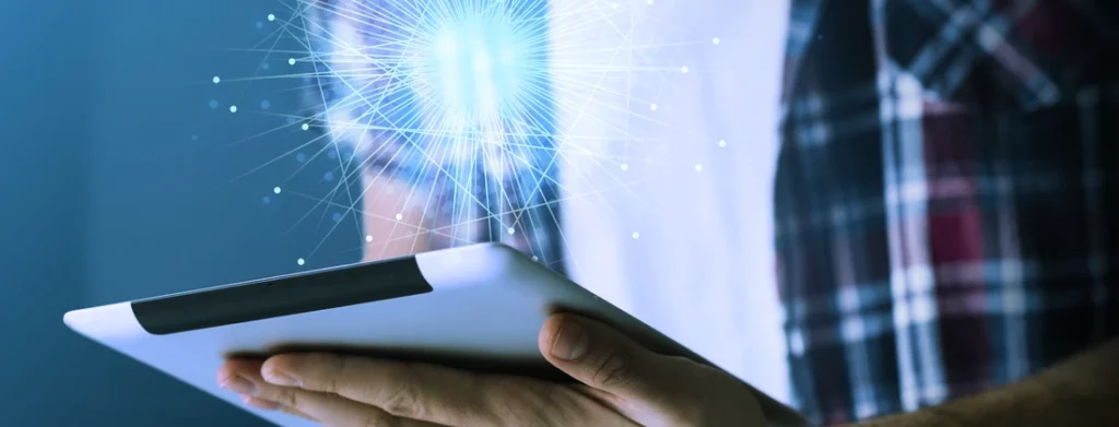 Person, die ein Tablet hält, während digitale Lichtstrahlen und Datenvisualisierungen entstehen.