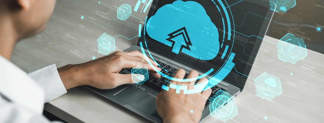 Person, die auf einer Laptop-Tastatur tippt, mit grafischen Cloud-Computing-Elementen im Hintergrund.