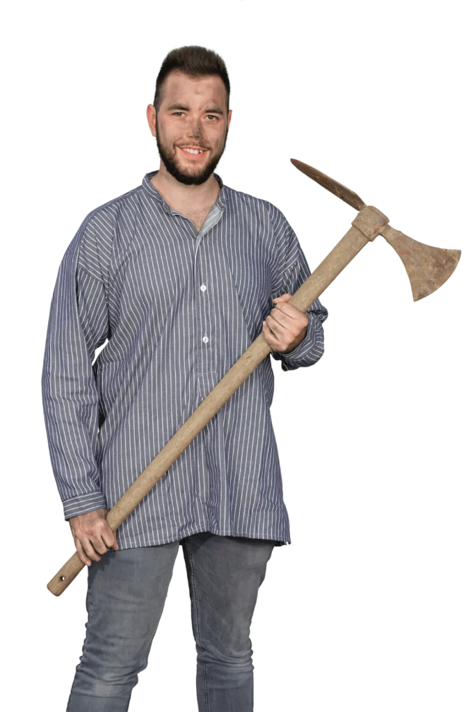 Mann in gestreifter Hemd mit einer Holzschaufel in der Hand, lächelt in die Kamera.