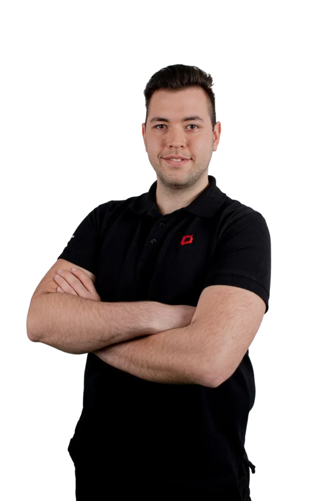 Florian Knauf in schwarzem Polo-Shirt mit verschränkten Armen vor schwarzem Hintergrund.