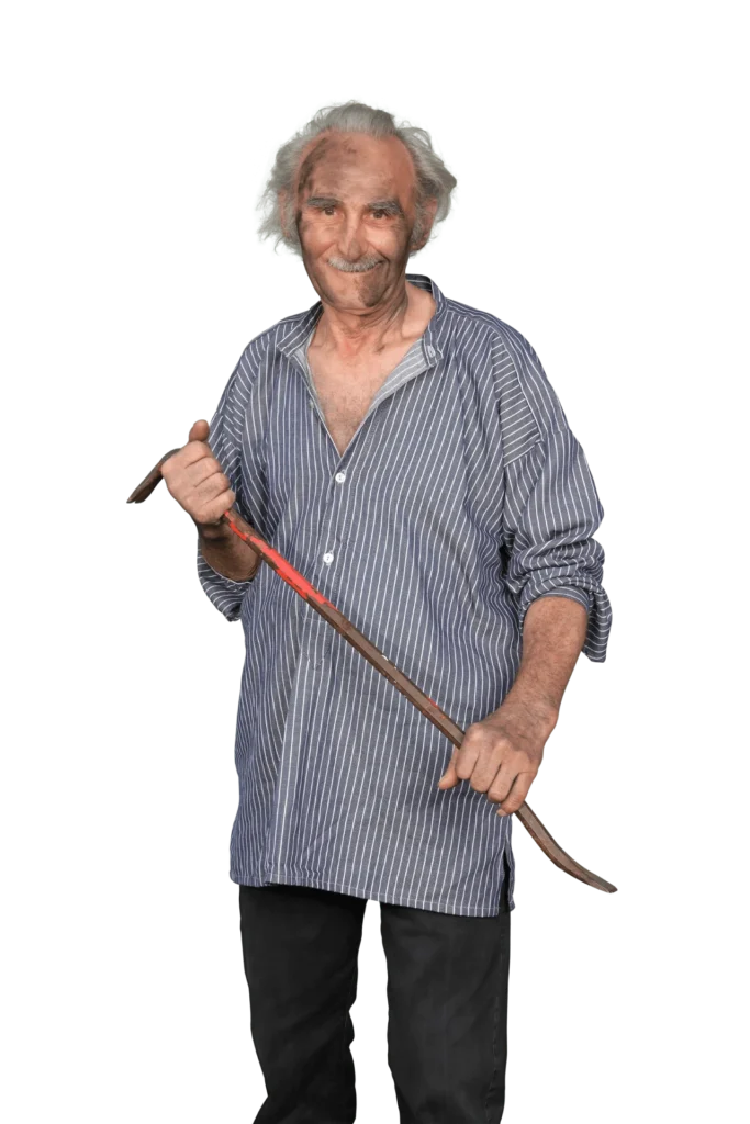 Älterer Mann mit grauen Haaren in gestreifter Bluse, hält einen Stock in der Hand.