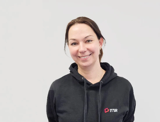 Maria in einem schwarzen Hoodie mit dem Logo von ITSR, lächelt vor einem neutralen Hintergrund.