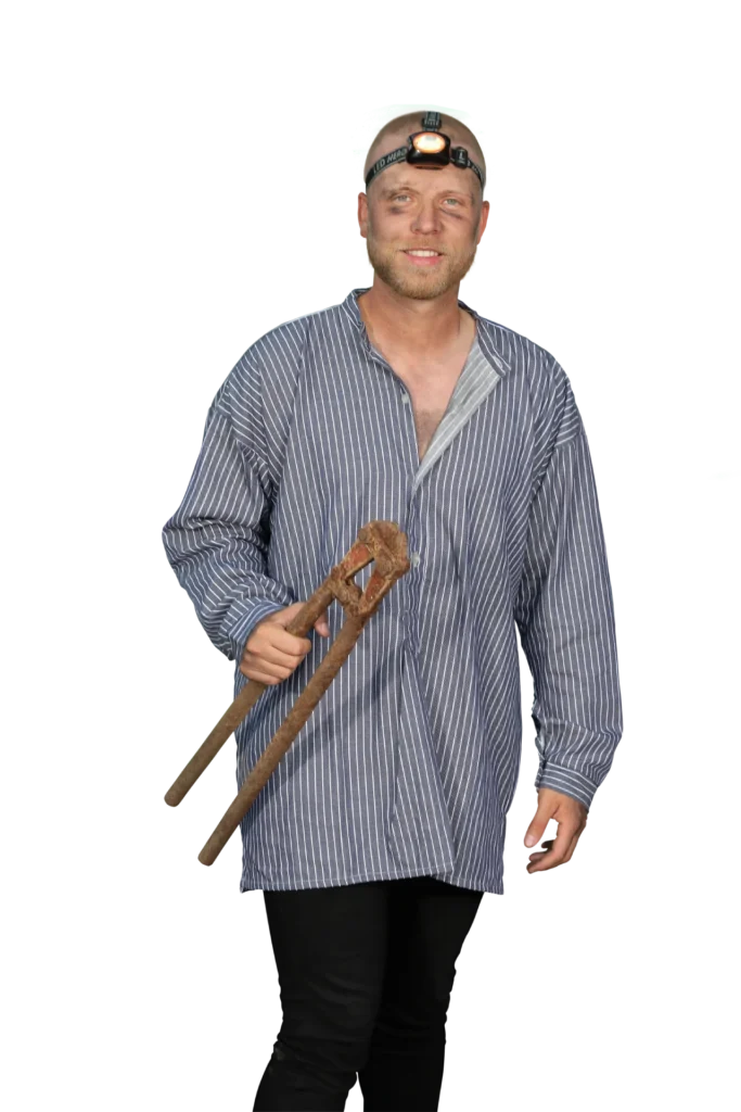 Mann in gestreifter Bluse mit einer Kopflampe und zwei Holzstöcken in der Hand.