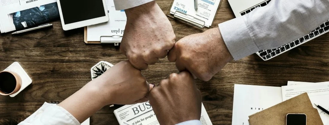 Drei Hände, die sich zu einem Fistbump treffen, um Teamarbeit und Zusammenarbeit zu symbolisieren.