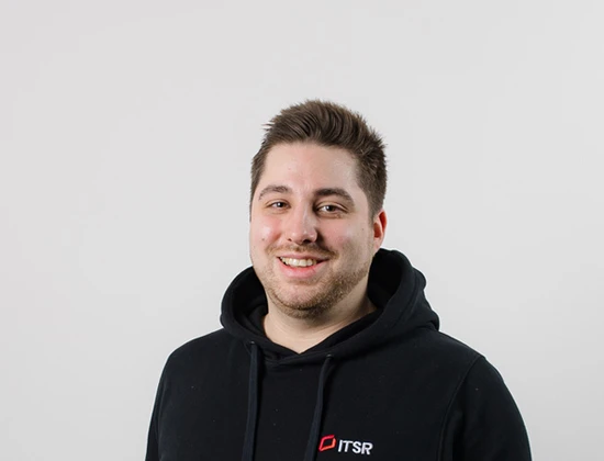 Manuel in einem schwarzen Hoodie mit dem Logo von ITSR, lächelnd vor einem neutralen Hintergrund.