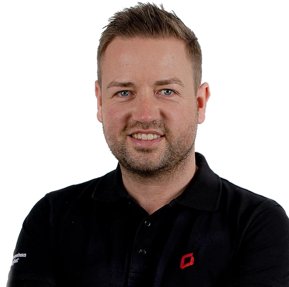 Nils lächelt in einem schwarzen Polo-Shirt mit einem roten Logo auf der linken Brustseite.